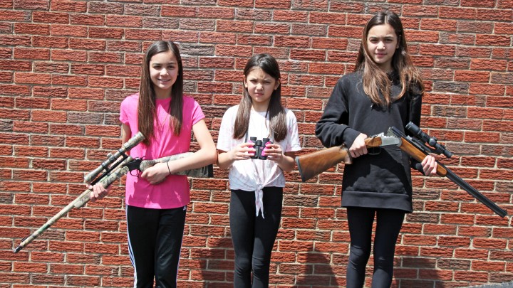 Three junior shooters posing with their optic-mounted air guns