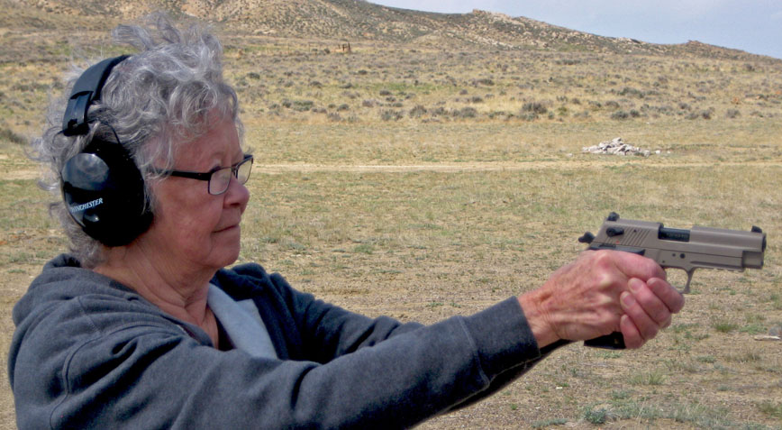 elderly woman takes aim with pistol